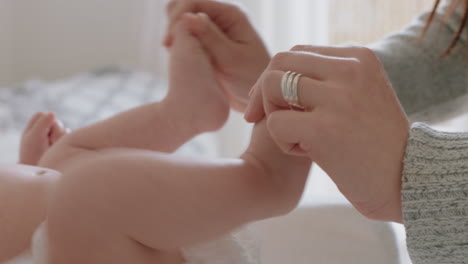 close up mother holding baby's feet playing with newborn caring for infant enjoying motherhood connection with child