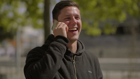 man talking by smartphone and laughing outdoor