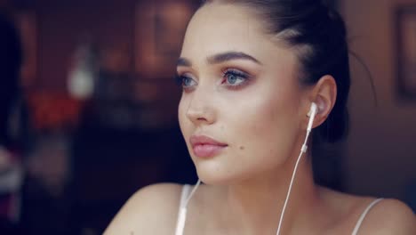 Young-gentle-girl-posing-in-headphones-and-looking-away-while-sitting