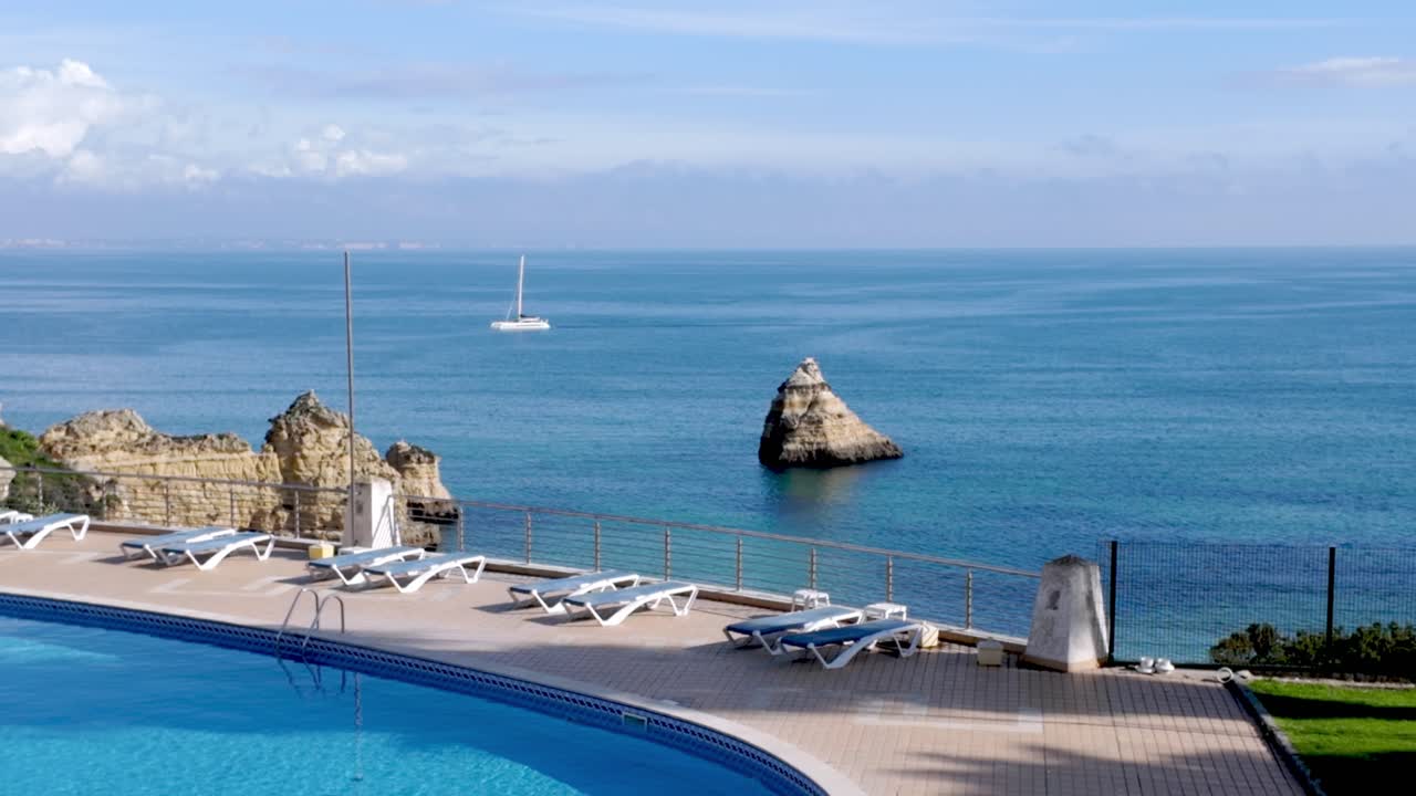 Ocean View from a Coastal Resort with Pool and Sailboat in Algarve, Portugal