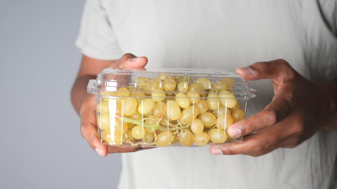 Person holding a container of grapes