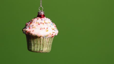 Cupcake-ornament-spins-about-on-a-silver-cord-in-front-of-a-green-screen