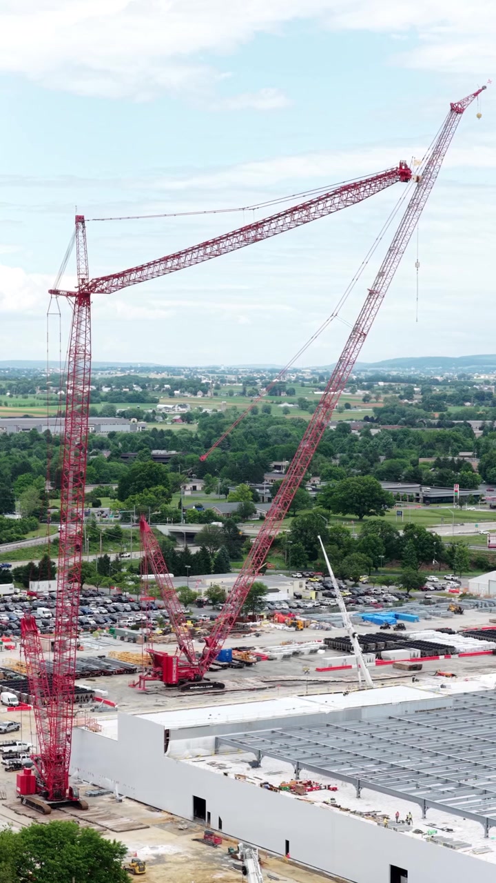 Aerial vertical drone footage of data center construction site with flying text animation, massive cranes, AI training facility, infrastructure investment