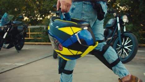 Close-up-shot-of-a-professional-biker-carrying-a-motorcycle-helmet-in-his-hands.-Preparing-to-ride-a-motorcycle