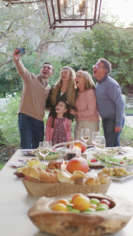 video vertical de padres caucásicos felices, hija y abuelos tomando selfies en la cena familiar