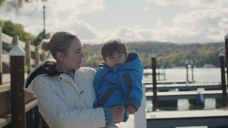 A-woman-with-a-child-in-her-arms-walks-along-the-pier,-in-the-distance-the-US-flag