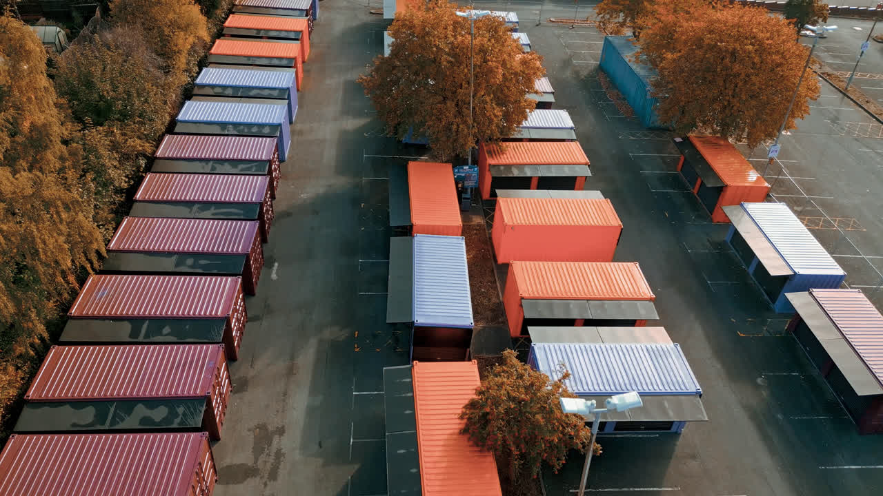 Luftoptagelser af flerfarvede skurvogne, markedsboder, stålkabiner og opbevaringsenheder, filmet direkte ovenfra og bevæger sig langsomt baglæns.