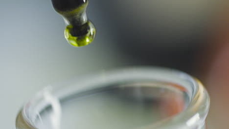 close-up capturing the moment a drop of colored liquid falls from a test tube into a beaker.
