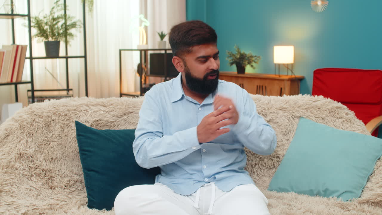 Indian man tries dancing uncertain moves then laughs shy embarrassed joyful fun practice inside room