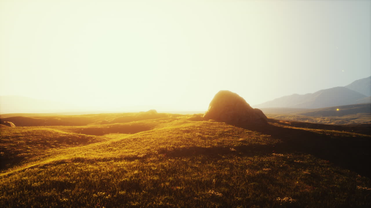 단 하나의 바위와 함께 굴러가는 필드에서 해가 뜨는