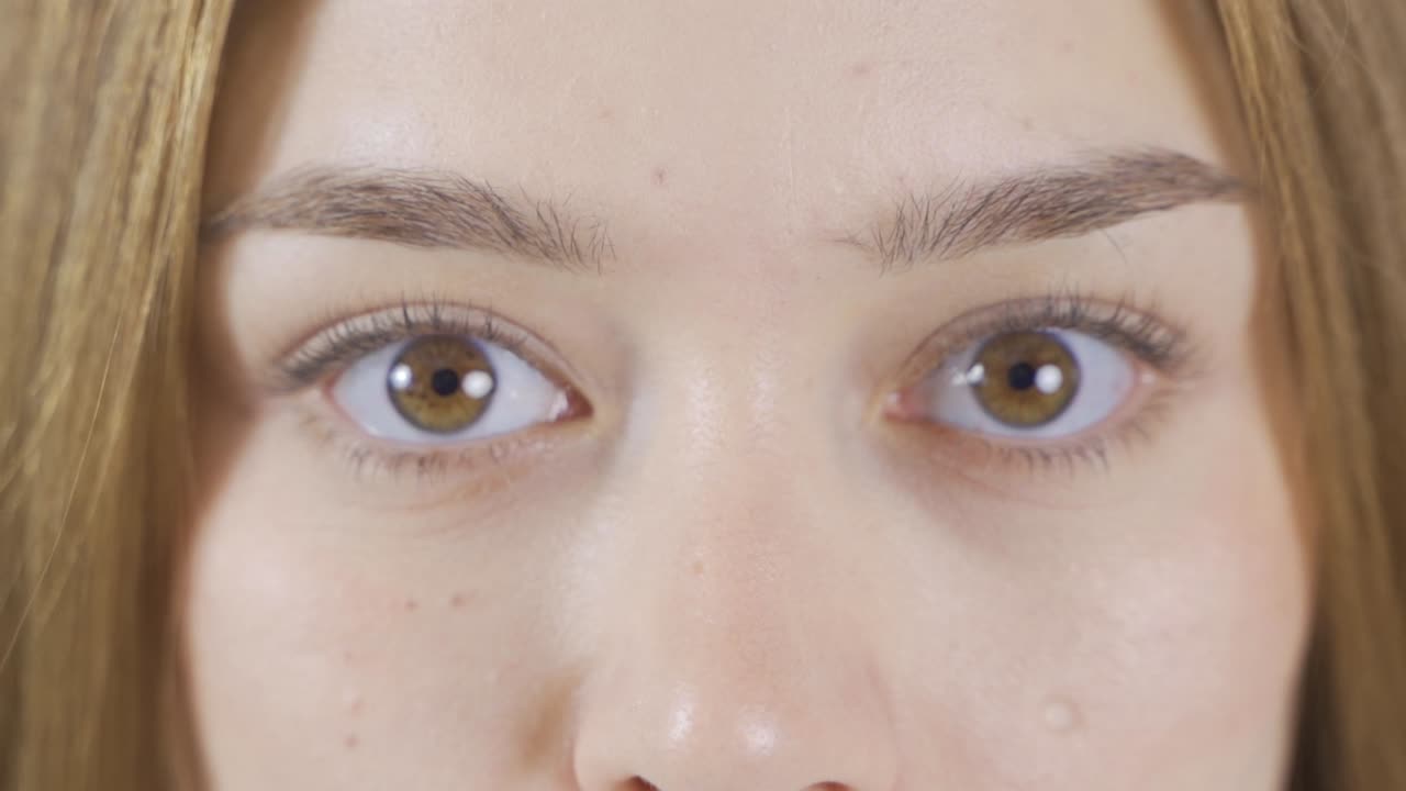 갈색 눈의 소녀가 슬로우 모션으로 카메라를 쳐다보고 있습니다.