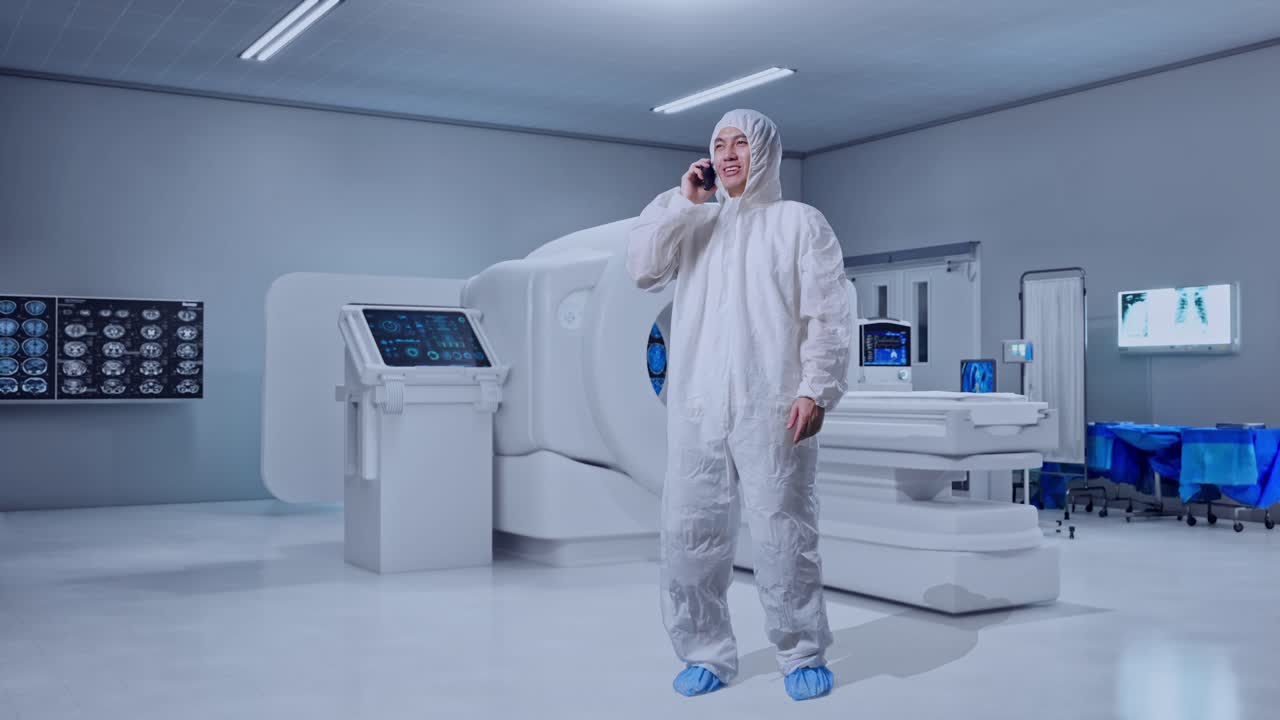 Full Body Of Asian Male Scientist Talking On Smartphone While Standing With MRI Machine In The Hospital