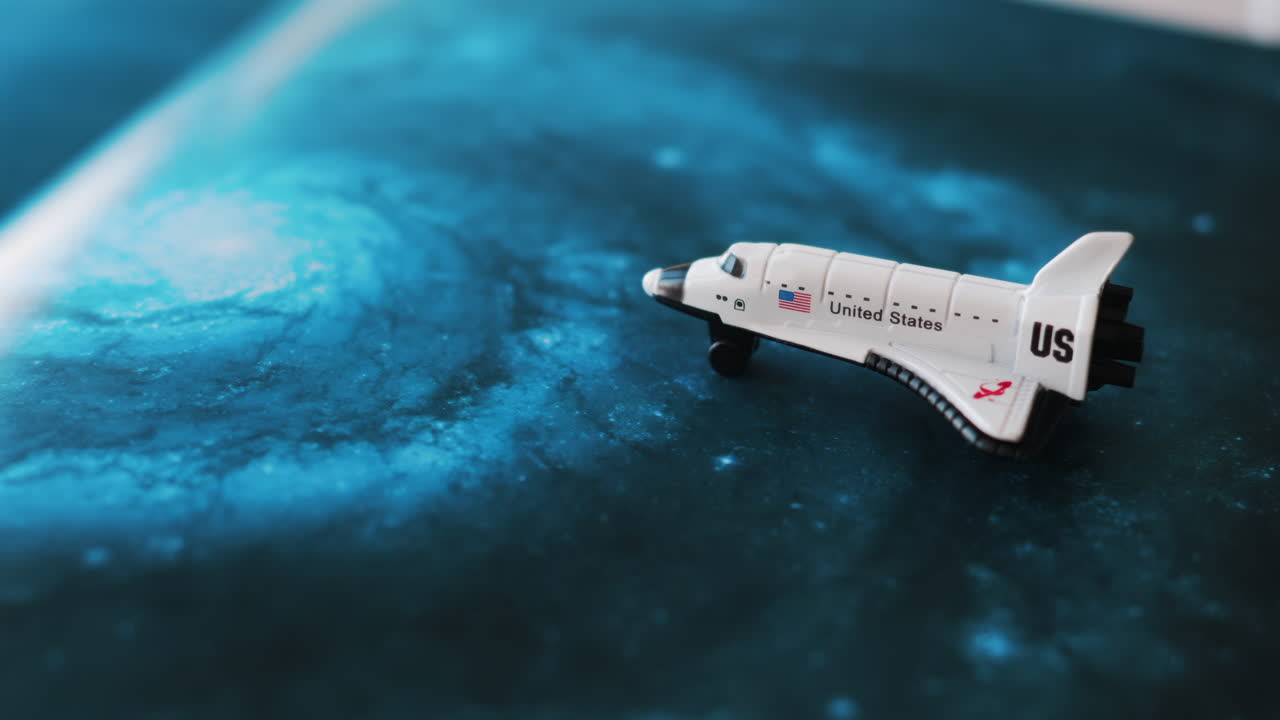 Close up of a miniature toy space shuttle placed on a blue cosmic galaxy backdrop