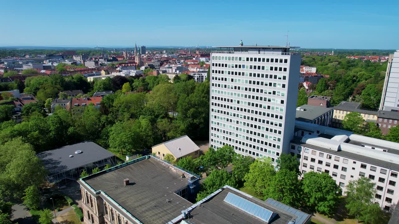 Okerhochhaus ved TU Braunschweig set på afstand med grønne træer om sommeren og byen Brunswick i baggrunden.