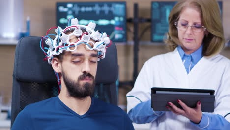 male patient with eyes closed while doctor checking brain activity