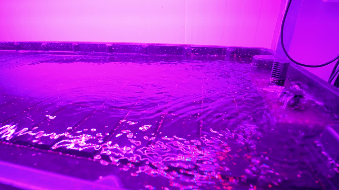 медленно вращающийся выстрел воды, входящий в вертикальную сельскохозяйственную технику под флуоресцентным освещением