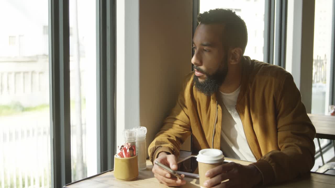 vista frontal de un joven de raza mixta mirando a través de la ventana en la cafetería 4k