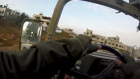 two israeli humvees driving on road through destroyed city streets in gaza