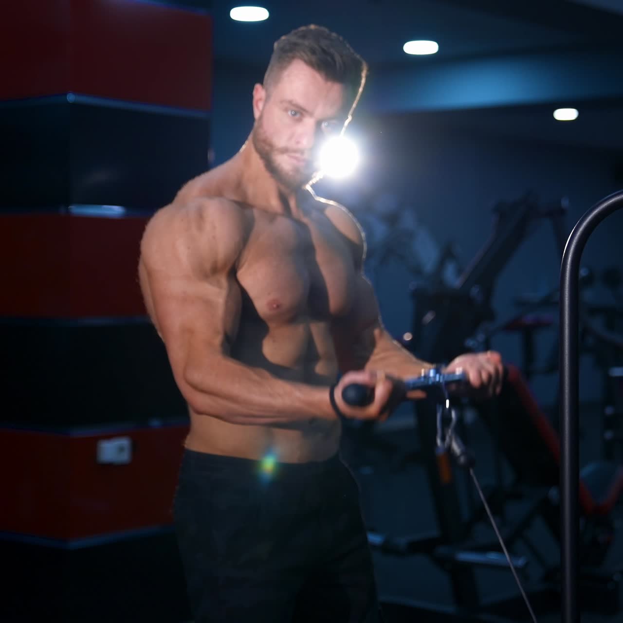Bodybuilder maschio a torso nudo si allena per le mani in una palestra moderna. Movimento lento