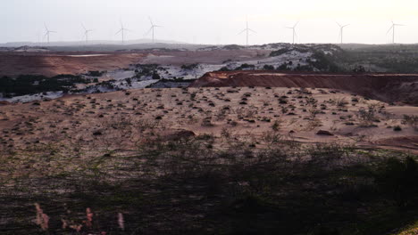 Toma-En-Gran-Angular-De-Las-Dunas-De-Arena-Con-La-Vista-De-Los-Molinos-De-Viento-Girando-En-El-Fondo-En-Vietnam-Durante-El-Día