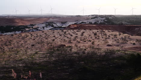 toma de ángulo alto de dunas de arena con vistas a molinos de viento girando en el fondo en vietnam durante el día
