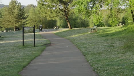 Point-of-View-Moving-Through-Park-with-Benches-and-Overflowing-Trash-Cans