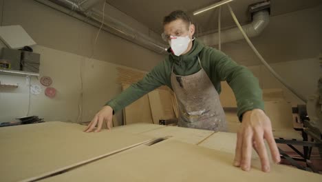 el carpintero corta tabla de madera, panel de contrachapado, madera en bruto en el taller utilizando una máquina de corte