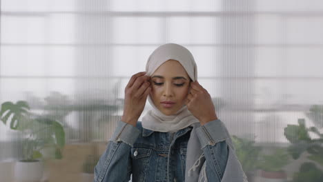 Porträt-Einer-Jungen-Muslimischen-Geschäftsfrau,-Die-In-Die-Kamera-Blickt-Und-Damit-Beschäftigt-Ist,-Im-Hintergrund-Ihres-Büroarbeitsplatzes-Ihr-Kopftuch-Vorzubereiten