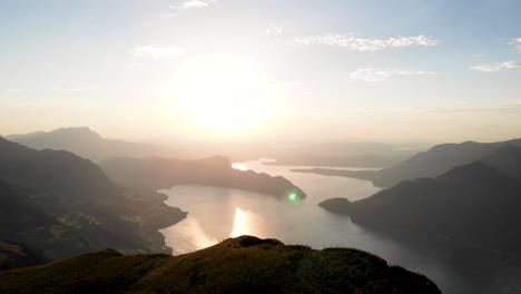 Sunset-aerial-flyover-alongside-the-edge-of-Niederbauen-Chulm-in-Uri,-Switzerland-with-a-view-of-Lake-Lucerne,-Burgenstock,-and-Pilatus-as-the-sun-set-on-a-summer-evening-in-the-Swiss-Alps