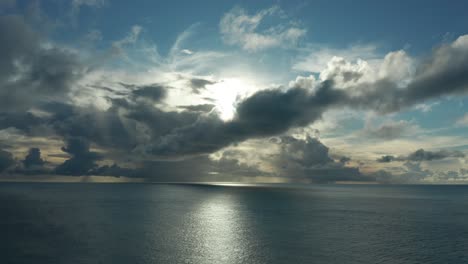 impresionante paisaje del sol brillante detrás de las nubes dramáticas sobre el océano azul profundo en una isla en fiji - plano general