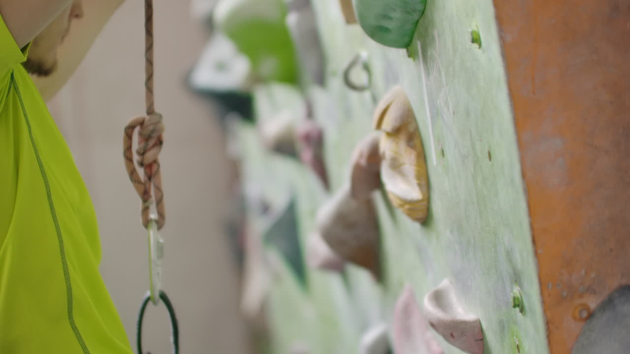 retrato de un escalador preparándose para escalar la pared en el pasillo para tiza sus manos y subir la pared con seguro en cámara lenta.