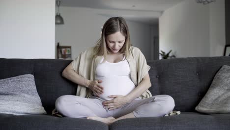 Front-view-of-pregnant-woman-rubbing-belly-and-talking-with-baby