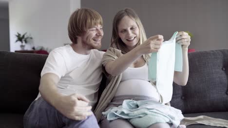 happy young couple looking at clothes for boy