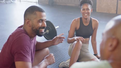 happy diverse group sitting and talking after training in fitness class at gym, in slow motion