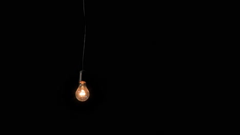 A-vintage-incandescent-lamp-with-black-wire-in-a-retro-style-shot,-warm-lighting-of-the-room,-isolated-look-on-the-dark-background,-abstract-idea-concept,-medium-handheld-shot