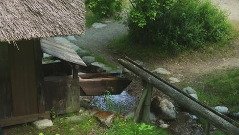 Water-Flowing-Out-Of-Bamboo-Pipe-Into-Watermill-Bucket-In-Shirakawago