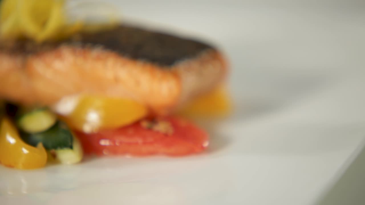 primer plano de un filete de salmón gourmet asado en una sartén servido con verduras de colores y una guarnición de limón