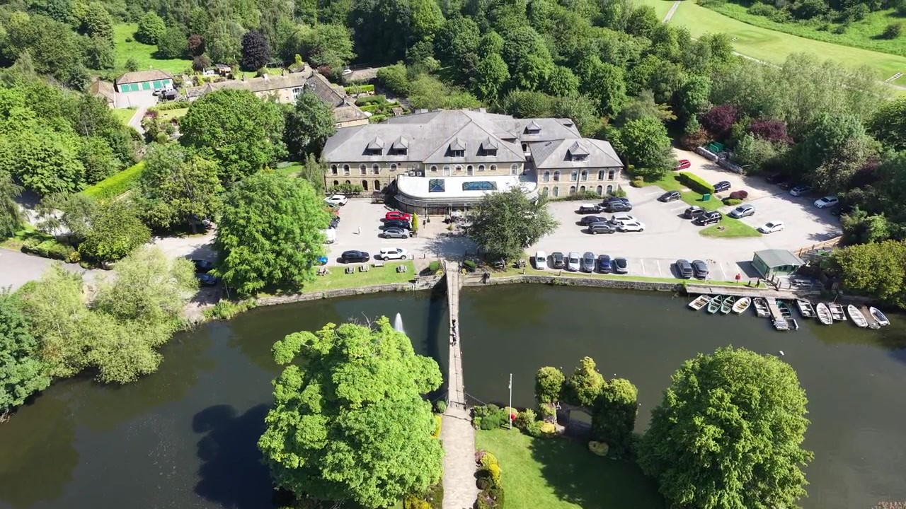 Luftaufnahme mit Drohne vom Boathouse in Balloch am Loch Lomond, Schottland. Flussrestaurant, Yachthafen, Brücke und Boote liegen am ruhigen Wasser, umgeben von Bäumen