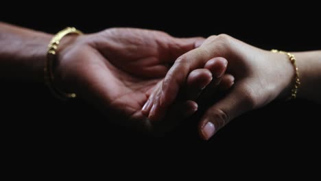 cinematic slomo two hands holding each other in studio lighting, female lady and a young girl coming together