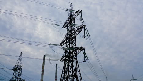 electrical pylons near the industrial pipes. high voltage electrical lines on the evening sky background. smoke from manufacture pollute the air.
