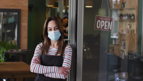 Retrato-De-Una-Peluquera-Con-Mascarilla-Apoyada-En-Una-Puerta-De-Cristal-En-La-Peluquería