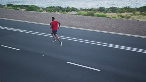 african american man exercising outdoors running on a coastal road