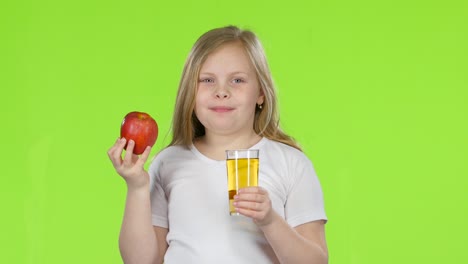 niño bebiendo jugo de manzana y sosteniendo una manzana