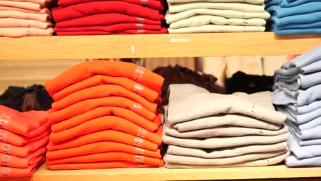 stacked clothing on shelves in a retail store