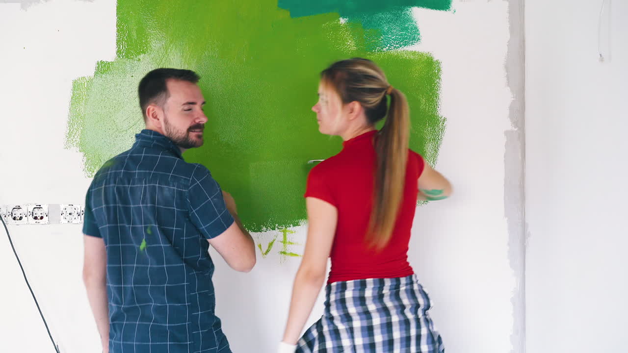 un hombre y una mujer encantadores pintan la pared con la palabra amor en la habitación