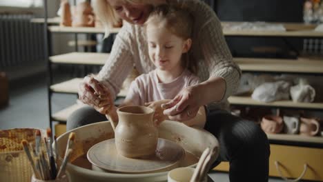 grandmother teaches her granddaughter working on a pottery rotating wheel