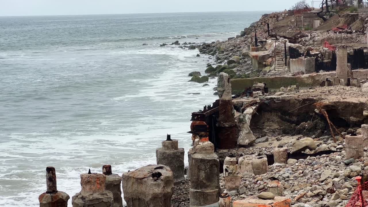 Handheld long lens booming up shot of oceanfront homes along Pacific Coast Highway burned by the Palisades Fire in Malibu, California. 4K