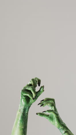 vertical video of halloween green monster hand with copy space on grey background