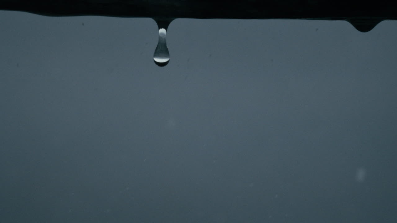 Minimalist shot of rope with rain drops glistening and falling in slow motion