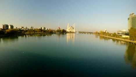 calm river, a mourning turkish flag and a huge central city mosque in the city of adana